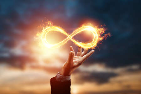 Infinity fire sign over hand of businessman on sunset backgrounの写真素材