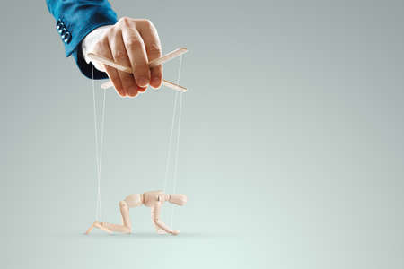 Male hand, puppeteer controls the puppet puppet with strings. A doll on her knees. The concept of world conspiracy, world government, manipulation, controlの写真素材