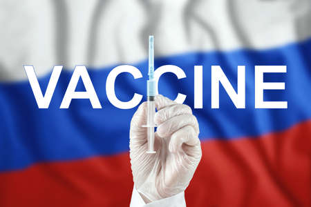 A syringe with a vaccine in the doctor's hand against the background of the Russian flag.  virus, immune protection, treatment against nCoV infection 2019, vaccinationの写真素材