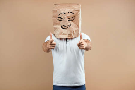 Men put a paper bag on their heads, point fingers at you, motivation support. Isolate on yellow background, images are easy to crop for use anywhere, copy spaceの写真素材