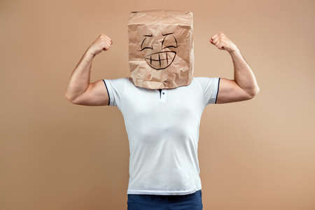 Men put a paper bag on their heads, shows strength, biceps, motivation, support, chorism. Isolate on yellow background, images are easy to crop for use anywhere, copy spaceの写真素材