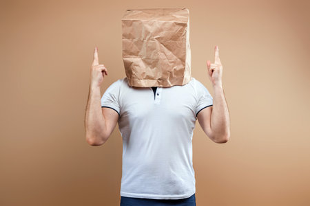 Men put a paper bag on their heads, showing thumbs up. Isolate on yellow background, images are easy to crop for use anywhere, copy spaceの写真素材