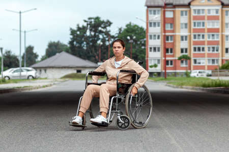A young disabled girl sits in a wheelchair on the street. The concept of a wheelchair, disabled person, full life, paralyzed, disabled person, health careの写真素材