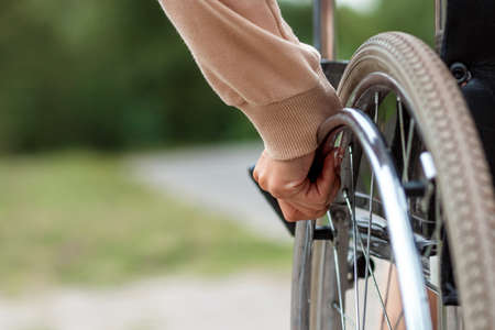 Close-up of a hand on a wheelchair wheel. The concept of a wheelchair, disabled person, full life, paralyzed, disabled person, happy lifeの写真素材