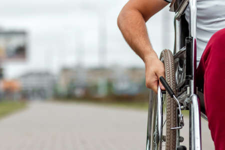 Close-up of a hand on a wheelchair wheel. The concept of a wheelchair, disabled person, full life, paralyzed, disabled person, happy lifeの写真素材