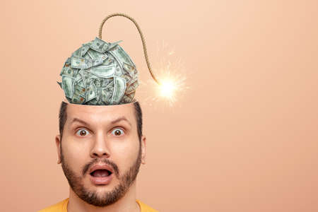 The man has a dollar bomb in his head that will explode soon. Financial crisis fear concept, bankruptcy, savings, fright, credit, debtsの写真素材