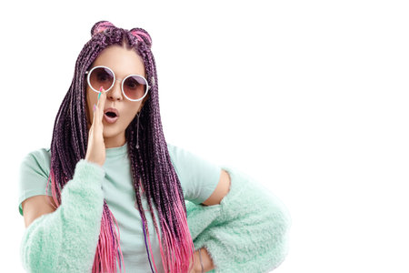 Girl with pink braids hairstyle in turquoise clothes and sunglasses isolate on a white background. Concept for modern style, inclusiveness, copy spaceの写真素材