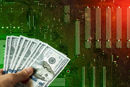 American dollars in hand on the background of a printed circuit board, electronic semiconductor...