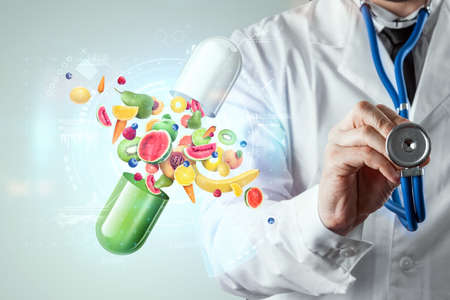 Food supplement in the form of medicinal capsules with fruits and vitamins on the background of the doctor. Correct diet, diet, alternative medicine, vitamins, naturopathy, homeopathy.の写真素材
