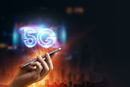 Creative background, a man's hand holds a phone with a 5G hologram on the background of the city. 5G...