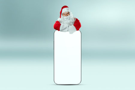 Smartphone mockup image, environment to showcase mobile app design, creative background. Smartphone for your advertising. Santa claus is standing next to a large smartphone. Christmas advertisementの写真素材