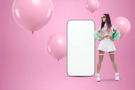 White screen smartphone mockup, environment to showcase mobile app design, creative background, smart phone for your advertisement. A creative girl stands next to a large smartphone. Copy spaceの写真素材