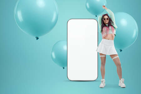 White screen smartphone mockup, environment to showcase mobile app design, creative background, smart phone for your advertisement. A creative girl stands next to a large smartphone. Copy spaceの写真素材
