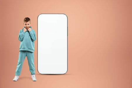 White screen smartphone mockup, environment to showcase mobile app design, creative background, smart phone for your advertisement. A cheerful boy stands next to a large smartphone. Copy spaceの写真素材
