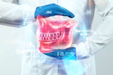 Medical poster, human skull anatomy, jaw x-ray, teeth snapshot. The doctor looks at the x-ray hologram of the jaw. Dentist, orthodontist, toothache, biteの写真素材