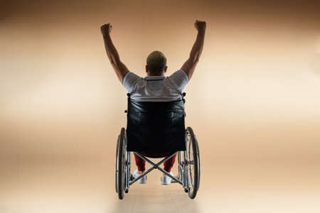 Silhouette of a disabled man in a wheelchair raised his hands. The concept of disability and illness, happiness, joy, successの写真素材