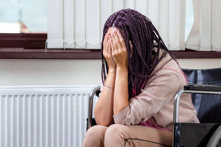 A beautiful modern girl sits in a wheelchair in depression, she is sad and lonely. Depression, opatija, disorder, psychological help, rehabilitationの写真素材
