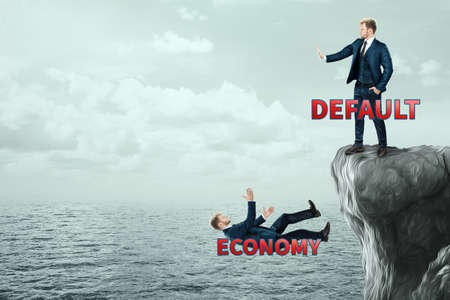 Default kills the economy. A businessman pushes another off a cliff. competition.の写真素材