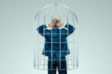Businessman in a suit in a metal cage. Possibilities are limited, business metaphor, mind prison, problems, difficultiesの写真素材
