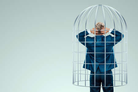 Businessman in a suit in a metal cage. Possibilities are limited, business metaphor, mind prison, problems, difficultiesの写真素材