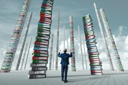 An unhappy office worker, a businessman, looks at the towers from many folders with documents....