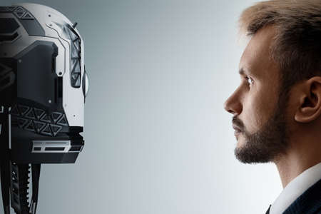 The face of a businessman and a robot opposite each other look into the eyes. Modern technologies, robot versus human, artificial intelligence, neural networks. 3D rendering, 3D illustrationの写真素材