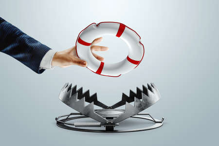 Businessman's hand throws a lifebuoy into a bear trap close-up. Concept of problem solving, failure, crisis, crisis management mixed mediaの写真素材