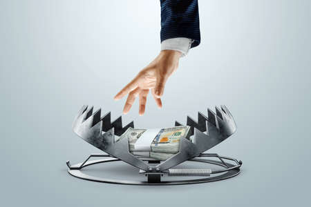 A man's hand takes dollars from a bear trap. The concept of mortgage, dirty money, bribe, corruption, easy money, debt, credit. mixed mediaの写真素材