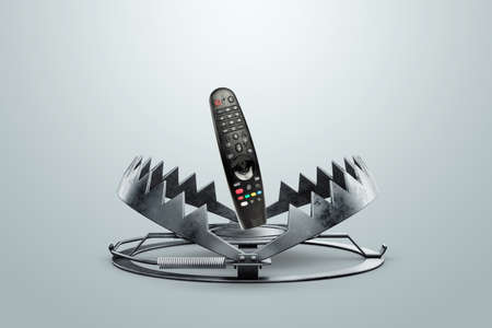 TV remote control in a metal bear trap, close-up. The concept of TV addiction, telemania, illnessの写真素材