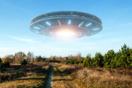 UFO, an alien saucer hovering above the field in the clouds, hovering motionless in the sky. Unidentified flying object, alien invasion, extraterrestrial life, space travel, spaceship. mixed mediaの写真素材