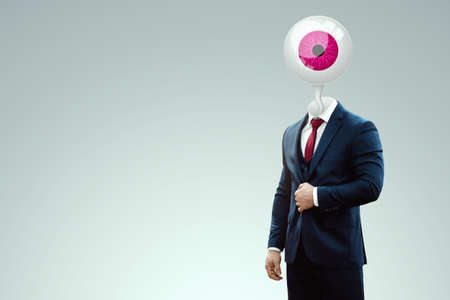 Progressive vision, vision, strategy and curiosity. Businessman in a suit with a pupil instead of a head. mixed mediaの写真素材