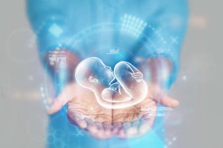 Medical concept, doctor's hands in a blue coat close-up and a hologram of a child. reproductive. Medical care, anatomy, artificial insemination. mixed media.の写真素材
