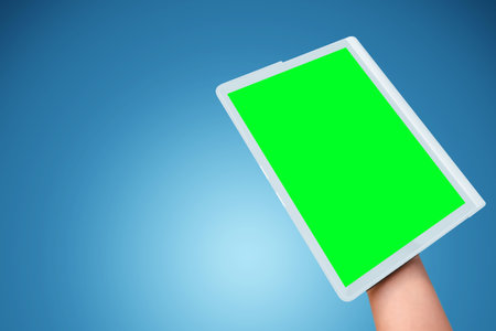 tablet in hand close-up, blue background.の写真素材