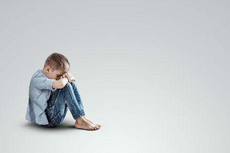 Stress, depression, emotional burnout. Malchi, the child sits with his head down on his knees, sad. Unhappy, in a bad mood. Modern design, magazine styleの写真素材