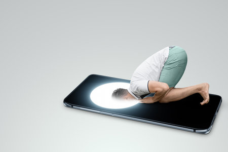 a man on his knees dives his head into the screen of a smartphone. Dependence on social networks, Internet addiction. social disease. Modern design, magazine styleの写真素材