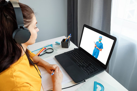 A girl makes a video call with her doctor from home. The concept of online medicine, new technologies, modern possibilities of medicineの写真素材