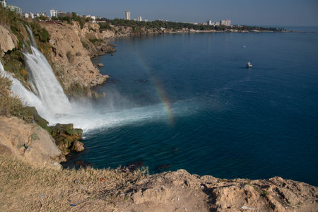 Beautiful view of the waterfall with rainbow, which flows into the seaの写真素材