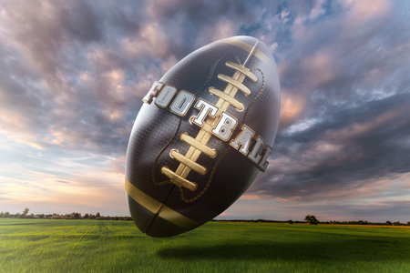 Creative image Black and gold Huge American football ball over a green field. American sports concept, grand final, strength, victory. Poster for advertising, design, copy space, mixed mediaの写真素材