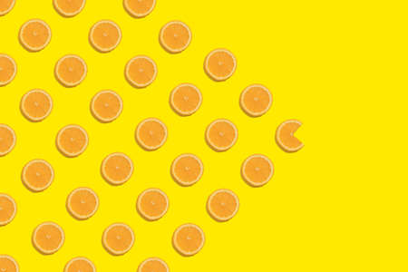 Slice of orange on a bright yellow background. Pattern on the left side and through the middle.の写真素材