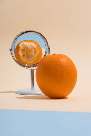 Orange on a light yellow-blue background with a reflection in the mirror. Shoot from Side. Balanced Elements in the Scene.の写真素材