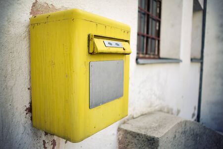 A bright yellow post box on the wall, close up.の写真素材