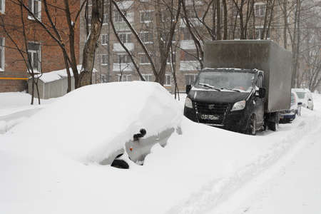 Moscow, Russia. 13th February 2021. A blizzard covered the city. A car is completely covered of snow. A car in the snow street.のeditorial素材