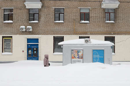 Moscow, Russia. 13th February 2021.A blizzard covered the city. A woman is walking on a sidewalk full of snowのeditorial素材