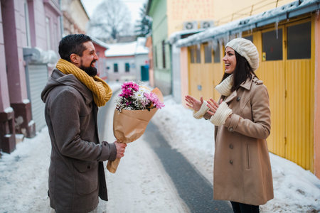 Man gives a girl flowers on the street with snow