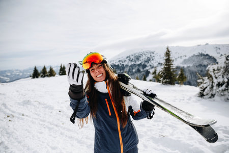Portrait of beautiful woman with ski and ski suit in winter mountainの写真素材