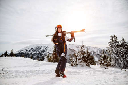 Portrait of beautiful woman with ski and ski suit in winter mountainの写真素材