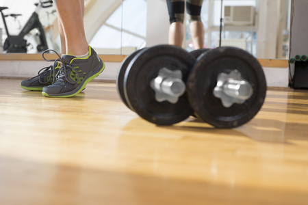 Dumbbells in a gym with the girls feet in a backgroundの写真素材