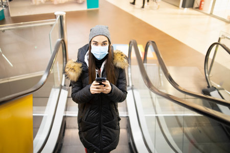 Young woman with a protective mask taking the stairs on an airport