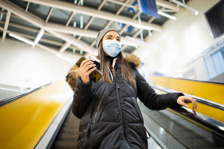 Young woman with a protective mask taking the stairs on an airportの写真素材