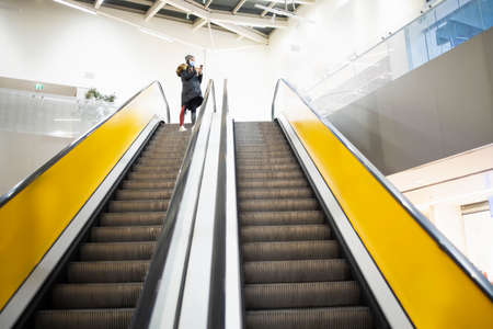 Young woman with a protective mask taking the stairs on an airportの写真素材